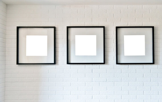 Group of wooden picture frames on white brick wall