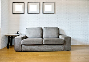 Gray couch with empty picture frames on wall