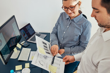 Fototapeta na wymiar Woman entrepreneur discussing financial data with her colleague standing at desk in office. Happy positive businesswoman working with charts and tables. Two people working together