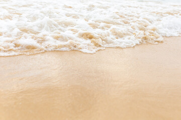 Beach sand sea water summer background. Sand beach desert texture. White foam wave sandy seashore...
