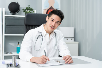 Fototapeta premium Portrait of Asian doctor sit on table in hospital and look at camera.