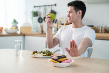 Obraz na płótnie Canvas Asian active handsome man reject donut and enjoying eat healthy food. 
