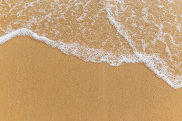 Beach sand sea water summer background. Sand beach desert texture. White foam wave sandy seashore top view