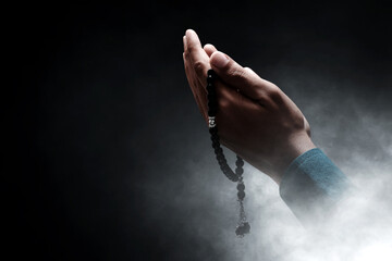 Muslim man praying with rosary beads