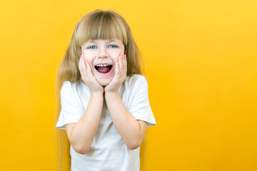 young surprised shocked crazy smiling baby girl holding hands isolated on yellow