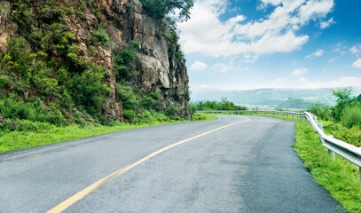 Winding road with steep rocky cliff in the mountains
