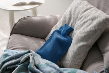 Rubber hot water bottle and checkered plaid on armchair indoors