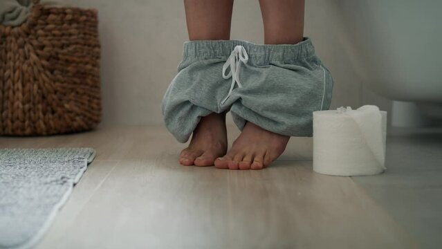 Detail of legs of woman sitting on toilet and holding a toilet paper roll. Shot with RED helium camera in 8K.    
