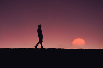 adult man silhouette in the mountain with a romantic sunset background