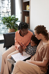 Young mothers helping toddler child to choose colors for pencil drawing