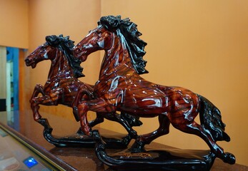 DISPLAY TWO HORSE STATUES, COLORED BROWN AND SHINE BLACK, ARE ON THE TABLE