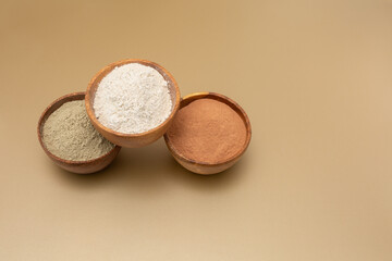 Organic green, red, white clay for facial mask on a beige background in wooden bowls. Home skin care concept.Self care.Copy space