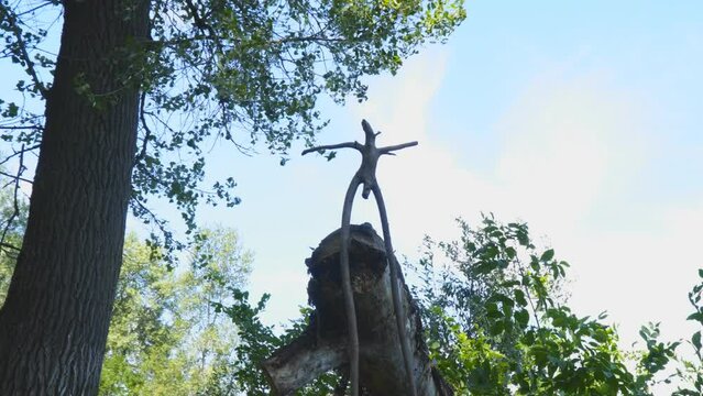 Silhouette wooden snag in the form of a pagan idol against the cloudy sky. Camera zoom in