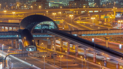 Fototapeta na wymiar Futuristic building of Dubai metro station and big junction behind in Dubai Marina aerial night timelapse