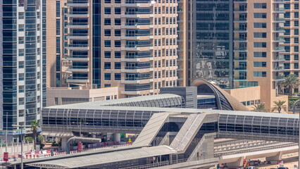 Futuristic building of Dubai tram station and luxury skyscrapers behind in Dubai Marina aerial timelapse, United Arab Emirates