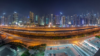 Panorama of Dubai Marina skyscrapers and Sheikh Zayed road with metro railway aerial night...