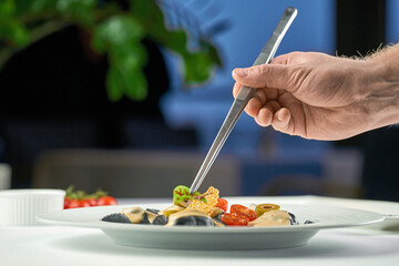 Chef decorating a dish of ravioli in a plate. Selective focus, shallow depth of field