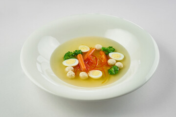 Soup with broccoli, vegetables and meat in a white plate on a white tablecloth