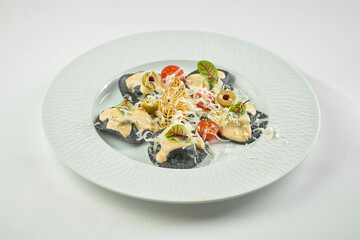 Black ravioli with red fish, sauce and tomatoes in a plate