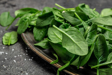 Close up Spinach. Raw organic fresh baby spinach leaves in a metal bowl on dark background. Food...