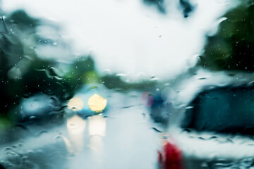 Heavy torrential rain through the windscreen. Cars with headlights on. Road safety. Selective focus