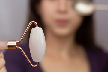 Closeup of a rose quartz roller and a cold spoon – tools that can be used to depuff face in the...