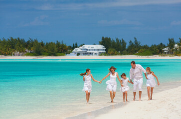 Happy Caucasian family white clothes walking tropical beach