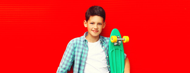 Portrait of teenager boy with skateboard on colorful red background
