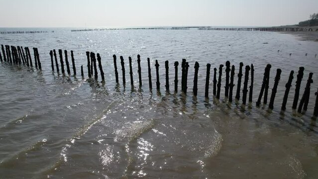 old wooden posts left in sea Fish traps on river Blackwater West Mersea Essex drone aerial footage