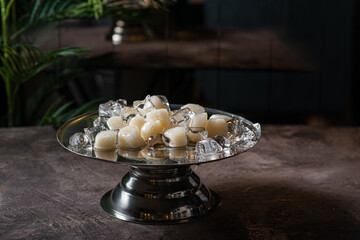 Fresh sea scallops among ice on a copper tray in a dark room