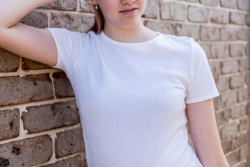 Girl wearing mockup white t-shirt on brick wall background. Template copy space