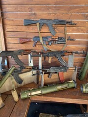 different types of weapons, a Kalashnikov assault rifle on the background of a wooden wall....