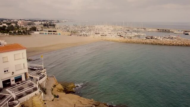 Aerial View Of Roc De Sant Gaieta With Waves On Empty Beach. Dolly Forward
