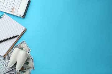 Flat lay composition with ceramic model of tooth and money on light blue background, space for...