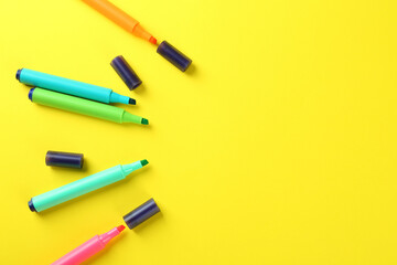 Many colorful markers on yellow background, flat lay. Space for text