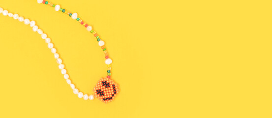 Banner with the chain with a smiley face pendant is made of multicolored beads and pearls on a...