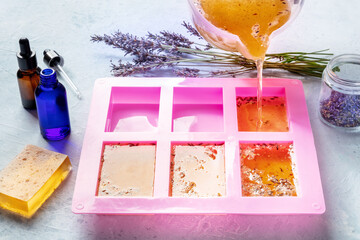 Soap making at home. Liquid glycerin with the additives of peels and flower buds poured into a...