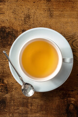 Tea in a white porcelain cup, shot from the top on a dark rustic wooden background