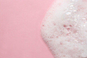 Fluffy bath foam on pink background, top view. Space for text