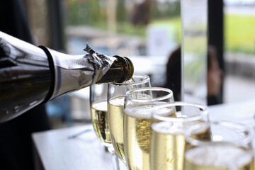 Pouring champagne from bottle into many glasses to celebrate the holiday after the wedding ceremony closeup
