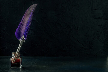 Purple quill pen with a retro ink well, a side view on a dark background, the concept of writing or...