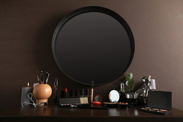Stylish round mirror hanging above dressing table with cosmetic products