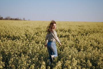 Woman run away through the flowering field and looking back