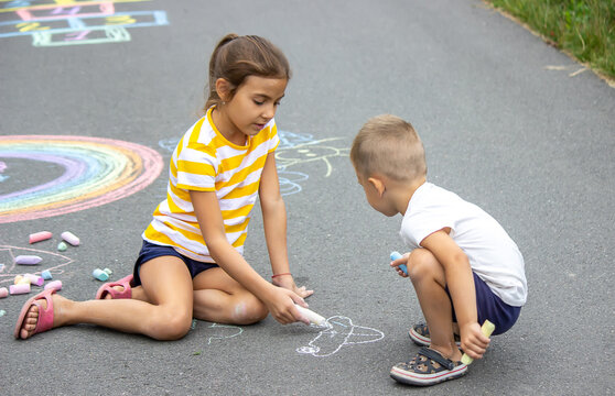 children draw on the pavement with chalk. Very good weather.