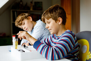 Two kids boys doing electric physical experiment as homework at home. Children study electricity....
