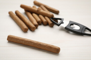 Cigars and guillotine cutter on white wooden table