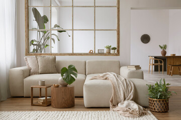 Stylish open space interior with design modular sofa, coffee tables, plaid, pillows, plants and...