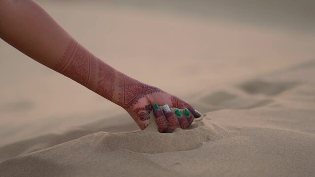 Closeup shot of hands of an Indian female lifting and pouring sand of the desert at Khuri Sand dunes in Thar Desert Jaisalmer, Rajasthan, India. Female pouring sand in the desert.