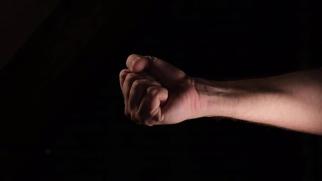 hand flips a coin heads or tails on a dark background