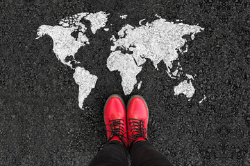 World map on an asphalt road and woman in shoes